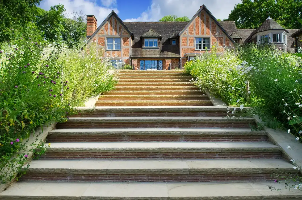 Stone steps rise through flowering borders towards the house at Shackleford